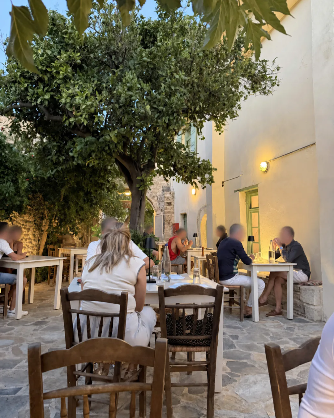 Evening tables beneath a tree in the stone courtyard at Taverna Aloni