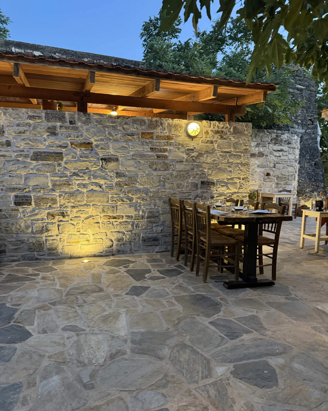 Stone courtyard and wooden tables at Taverna Aloni in Agioi Deka