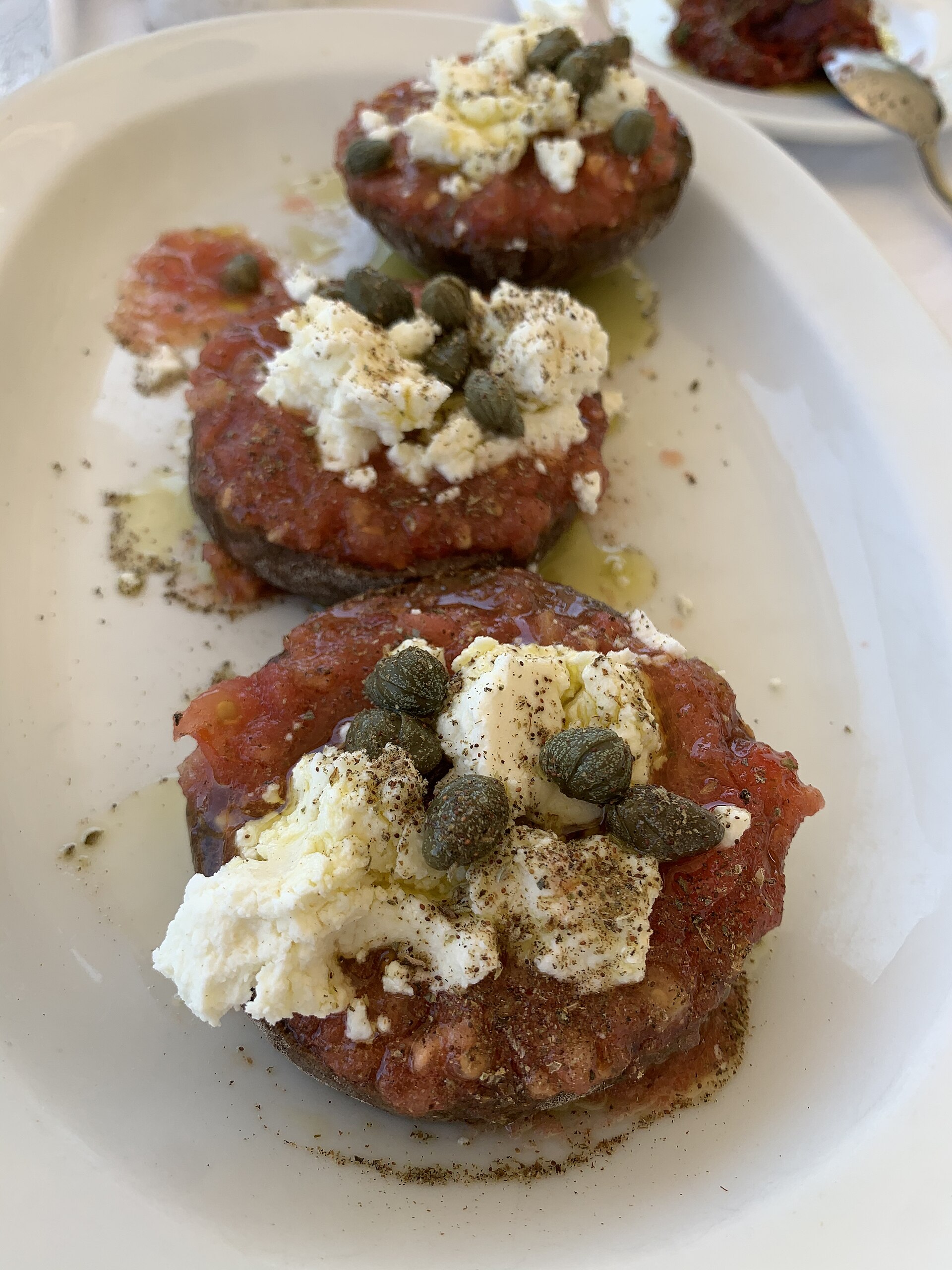 A plate of dakos in Crete: barley rusk soaked with grated tomato, olive oil, and crumbled myzithra cheese, topped with olives.
