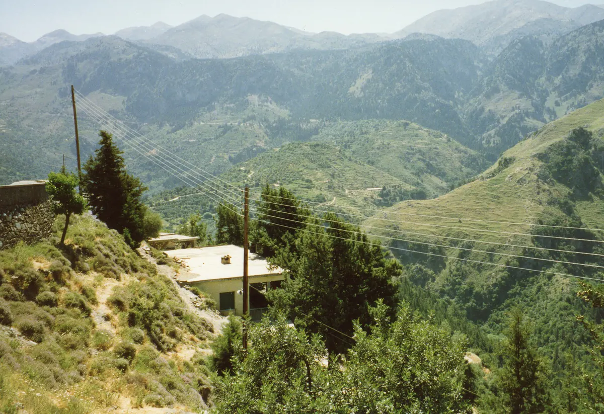 The winding mountain road climbing toward the Samaria Gorge on Crete, switchbacks cut into bare limestone slopes.