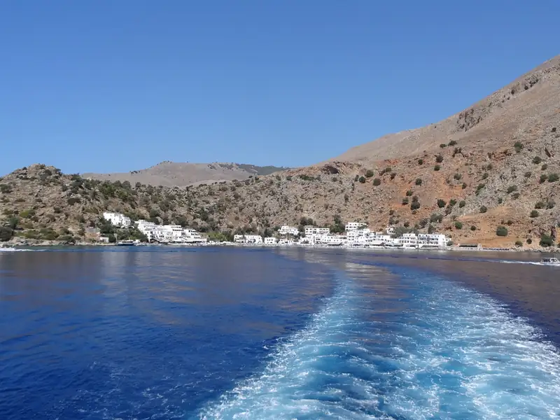 Loutro's white houses below bare mountains, seen from the ferry.