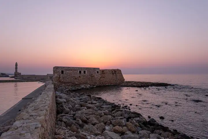 Chania's Venetian harbor and lighthouse at sunset.
