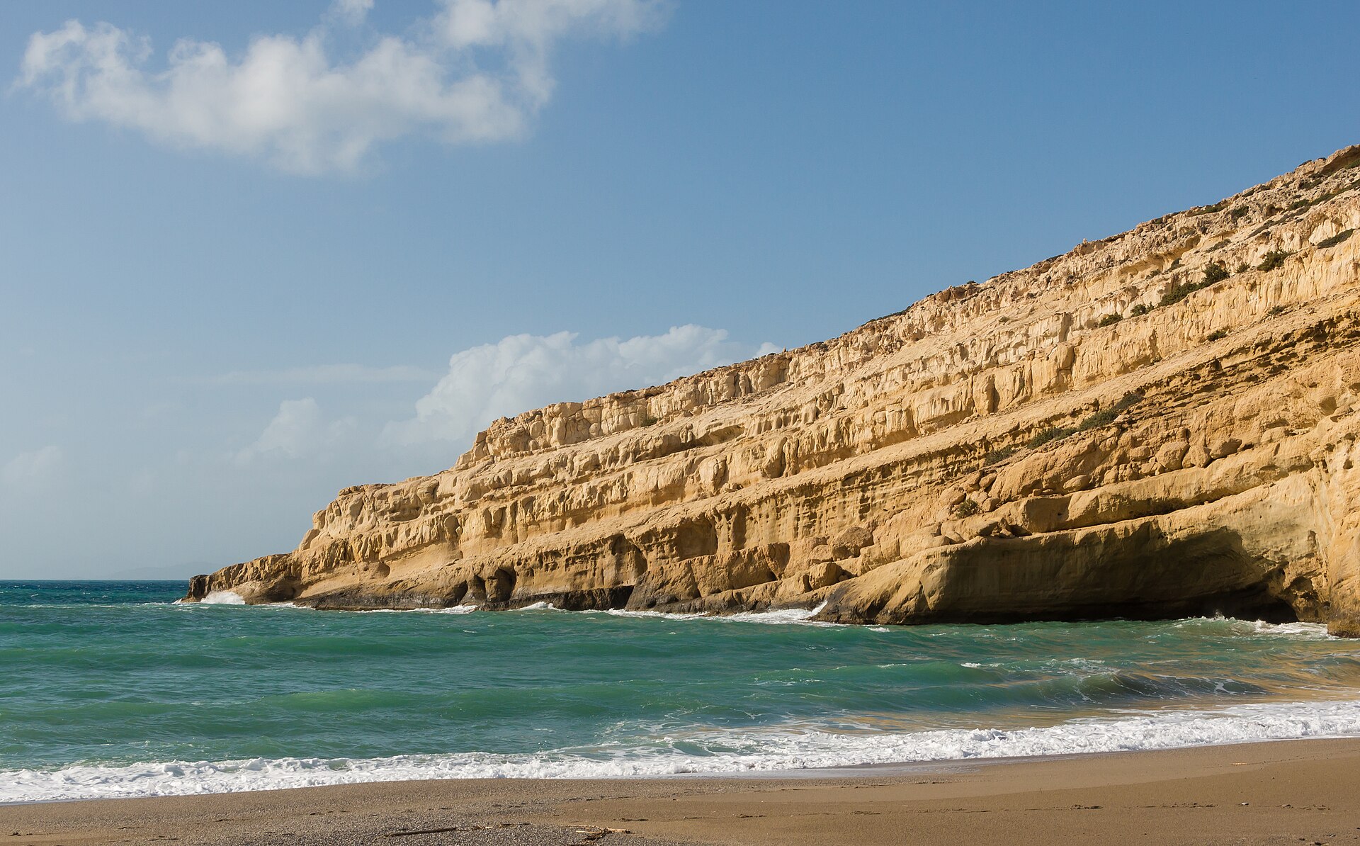 The sandstone cliff at Matala on the south coast of Crete, honeycombed with hollowed Roman-era cemetery caves above the beach